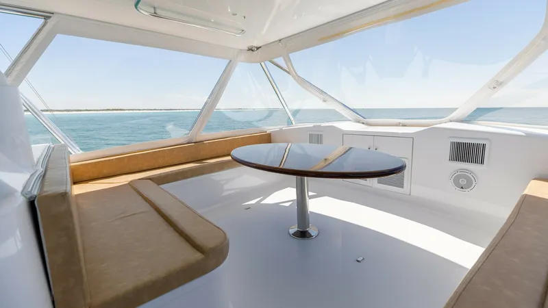Slide: The Image of Flybridge Seating Area with Ocean View This inviting flybridge features plush, L-shaped seating surrounding a polished wooden table, perfect for socializing while enjoying panoramic ocean views. The expansive windows provide ample natural light, enhancing the spacious feel of the area. Modern - 7469774