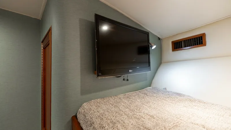 Slide: The Image of Guest Cabin with TV This cozy guest cabin features a plush bed with modern bedding, perfect for relaxation. A flat-screen TV is mounted on the wall, providing entertainment in a comfortable setting. The cabin's soft lighting and elegant finishes create a welcoming and restfu - 7469764