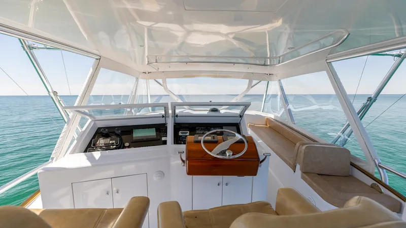 Slide: The Image of Flybridge Helm Station The flybridge helm station of the 2006 Blackwell 65 Convertible offers an expansive view, featuring a sleek wooden steering wheel and modern navigation instruments. Plush seating ensures comfort for both captain and guests, while the panoramic windows pro - 7469771