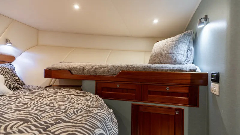 Slide: The Image of Guest Cabin with Upper Berth This inviting guest cabin features a comfortable upper berth, accented by rich wood cabinetry that provides ample storage. The soft, ambient lighting enhances the cozy atmosphere, making it a perfect retreat for guests. The tasteful bedding and modern fix - 7469765