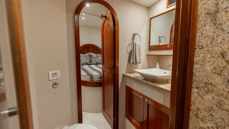 Slide: The Image of Luxurious Ensuite Bathroom This elegant ensuite bathroom on the 2006 Blackwell 65 Convertible features a stylish vessel sink atop a granite countertop, complemented by rich wood cabinetry. The space is well-lit with recessed lighting, creating a warm and inviting atmosphere. A door - 7469768