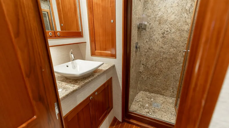 Slide: The Image of Luxurious Ensuite Bathroom with Shower This elegant ensuite bathroom on the 2006 Blackwell 65 Convertible features exquisite wood paneling and a polished granite countertop. The spacious glass-enclosed shower boasts matching granite walls, providing a luxurious and cohesive aesthetic. Ample st - 7469758