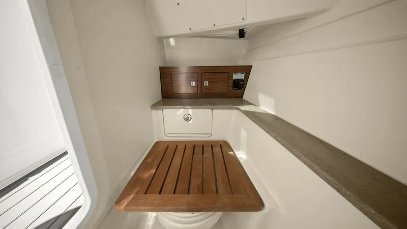 Slide: The Image of Compact Head with Teak Accents This image showcases the compact and efficient head of the 2019 Boston Whaler 320 Vantage. The space is designed with functionality in mind, featuring a teak lid over the toilet for added utility and aesthetic appeal. The use of wood and stainless-steel f - 7469819