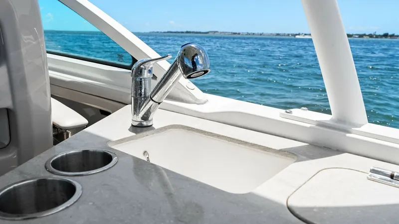 Slide: The Image of Cockpit Wet Bar Area The cockpit wet bar of the 2019 Boston Whaler 320 Vantage features a sleek countertop with a built-in sink and chrome faucet, perfect for entertaining on the water. Stainless steel cup holders provide convenience, while the open design ensures easy access - 7469843