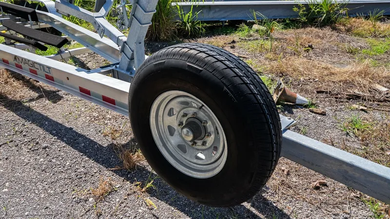 Slide: The Image of Boat Trailer Wheel and Frame This image showcases a sturdy boat trailer designed for easy transportation of vessels like the Boston Whaler 320 Vantage. Featuring a robust wheel and frame, the trailer ensures stability and durability on various terrains. The galvanized metal construct - 7469869