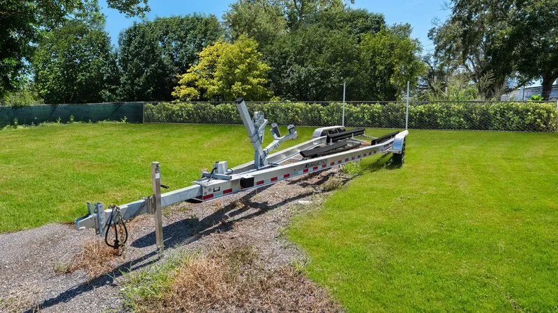 Slide: The Image of Boat Trailer in Grassy Yard This image showcases a robust boat trailer positioned in a lush, green yard, ready to accommodate the Boston Whaler 320 Vantage. The trailer's sturdy metal construction ensures durability, making it ideal for transporting the vessel safely. Surrounded by - 7469871