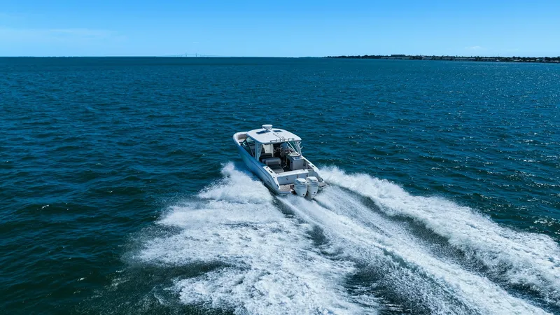 Slide: The Image of Aerial Aft View Underway This dynamic aerial shot captures the Boston Whaler 320 Vantage, 'Thou Shell Knot', gracefully cutting through the waves. The 2019 model showcases its powerful twin engines, leaving a striking wake behind. The open cockpit design provides ample seating, m - 7469854