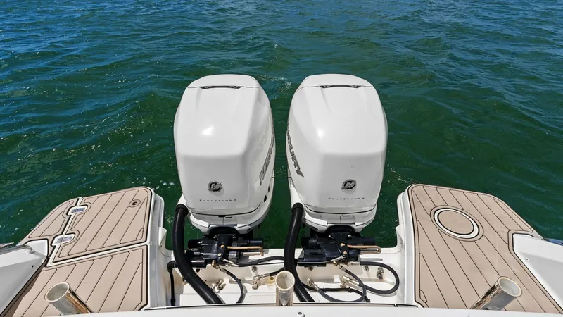 Slide: The Image of Twin Outboard Motors on Aft Deck This image showcases the powerful twin outboard motors on the aft deck of the 2019 Boston Whaler 320 Vantage. The sleek, white Mercury engines provide exceptional performance and reliability, perfect for long voyages. The deck features elegant teak floori - 7469835