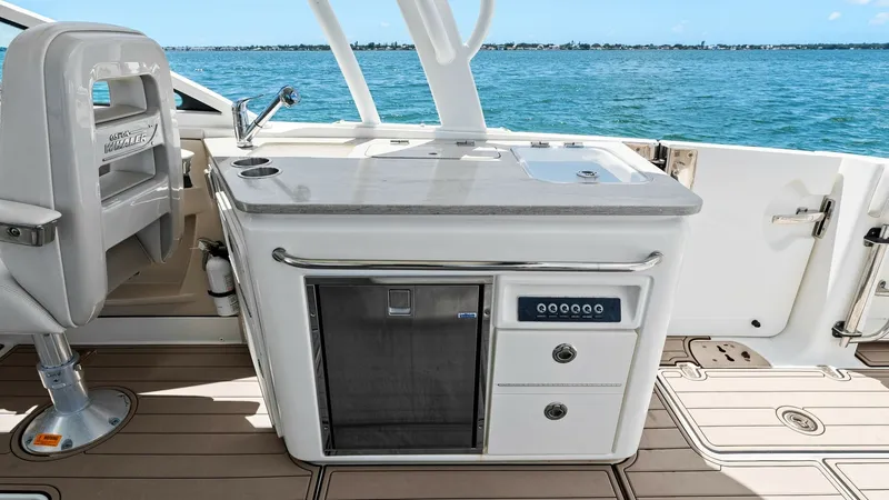 Slide: The Image of Cockpit Wet Bar and Grill Area The cockpit of the 2019 Boston Whaler 320 Vantage features a sleek wet bar equipped with a grill, sink, and storage drawers, perfect for entertaining. The polished countertop and stainless steel accents provide a modern, stylish look, while the built-in r - 7469842