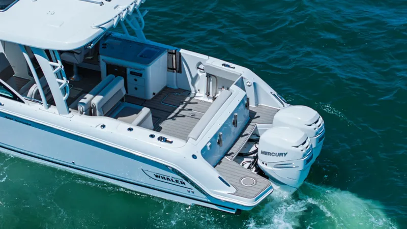Slide: The Image of Aft Deck with Dual Engines The Boston Whaler 320 Vantage's aft deck offers a spacious layout with comfortable seating and versatile amenities. Featuring dual Mercury outboard engines, this area is designed for both relaxation and performance. The teak-like flooring adds a touch of - 7469853