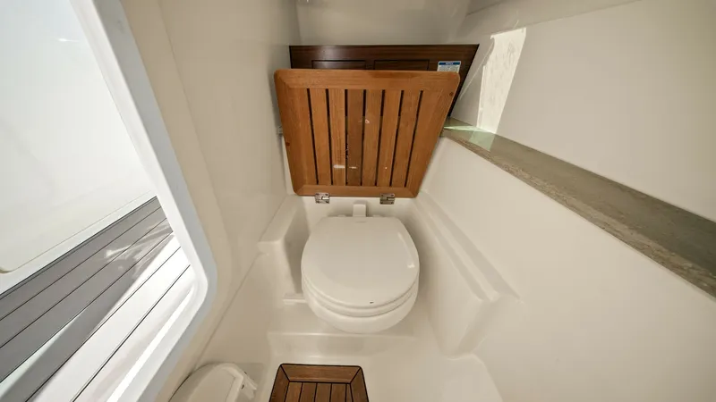 Slide: The Image of Compact Marine Head with Teak Accents This image showcases the well-appointed marine head of the 2019 Boston Whaler 320 Vantage. The space features a sleek white finish complemented by rich teak accents, providing both functionality and style. The compact design maximizes utility, ensuring co - 7469820