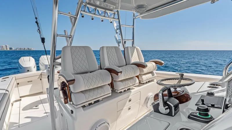 Slide: The Image of Helm Station with Triple Seating This image showcases the helm station of the 2025 Valhalla Boatworks V-41, featuring three luxurious, diamond-stitched captain's chairs. The sleek console is equipped with state-of-the-art controls and a polished steering wheel, offering both functionalit - 7517254