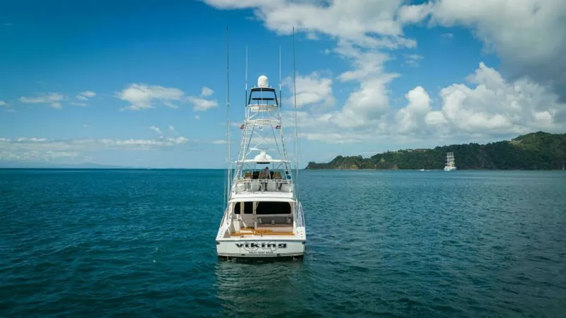 Slide: The Image of Aft View with Tower and Sea This image captures the impressive aft view of the 2023 Viking 64 Convertible, Twin Reels. The sleek design showcases the spacious cockpit ideal for fishing, complemented by the towering flybridge that offers panoramic ocean views. The vessel's name is pr - 7600572