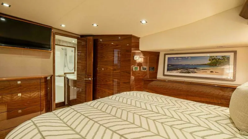 Slide: The Image of Luxurious Master Stateroom The master stateroom of the 2023 Viking 64 Convertible exudes opulence with its rich wood finishes and contemporary lighting. The room features a comfortable, stylish bedding arrangement complemented by a large flat-screen TV for entertainment. Elegant ca - 7600526