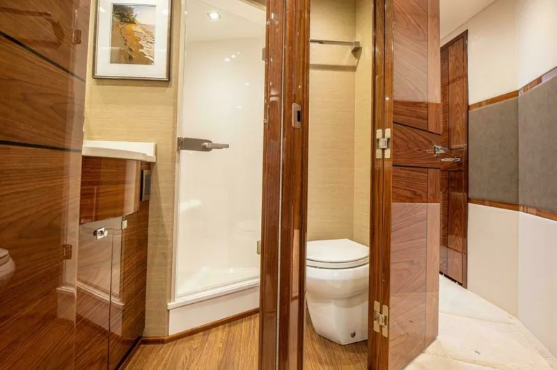 Slide: The Image of Luxurious Ensuite Bathroom View This image showcases the elegant ensuite bathroom of the 2023 Viking 64 Convertible. Rich wooden cabinetry and doors contrast beautifully with the modern fixtures, offering both style and functionality. The shower area features sleek glass doors, and the - 7530850