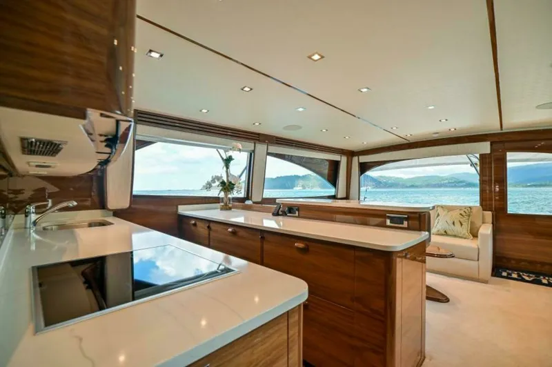 Slide: The Image of Spacious Salon with Galley View The salon of the 2023 Viking 64 Convertible is elegantly designed with panoramic windows offering breathtaking views. The galley features high-end appliances and sleek countertops, providing a perfect blend of functionality and style. Rich wood finishes a - 7530832