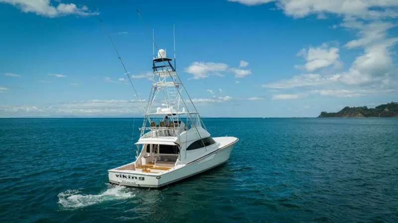 Slide: The Image of Aft View with Tower and Cockpit This image showcases the sleek aft view of the 2023 Viking 64 Convertible, highlighting its spacious cockpit and towering tuna tower. The vessel's clean lines and robust design are complemented by the open sea backdrop, emphasizing its prowess for offshor - 7530885