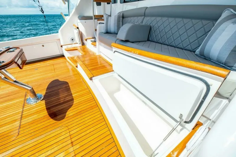 Slide: The Image of Cockpit Seating with Storage Access The cockpit of the 2023 Viking 64 Convertible offers luxurious seating with diamond-stitched upholstery, providing comfort and style. Beneath the seating, a convenient storage compartment is accessible, perfect for stowing gear and essentials. The teak fl - 7530876