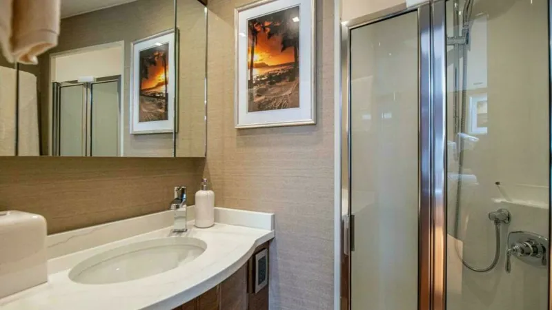 Slide: The Image of Elegant Ensuite Bathroom This beautifully appointed ensuite bathroom on the 2023 Viking 64 Convertible features a sleek glass-enclosed shower and a stylish vanity with a polished countertop. The warm wood finishes complement the modern fixtures, while the artful decor adds a touc - 7600540