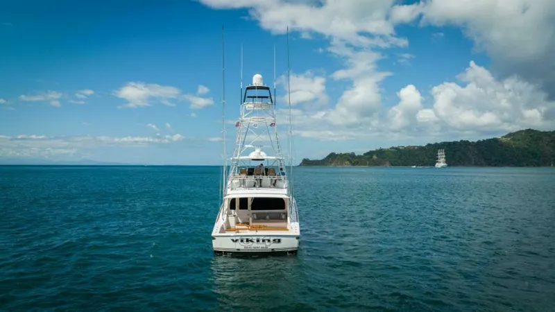 Slide: The Image of Aft View with Tower and Sea This image captures the impressive aft view of the 2023 Viking 64 Convertible, Twin Reels. The sleek design showcases the spacious cockpit ideal for fishing, complemented by the towering flybridge that offers panoramic ocean views. The vessel's name is pr - 7530890