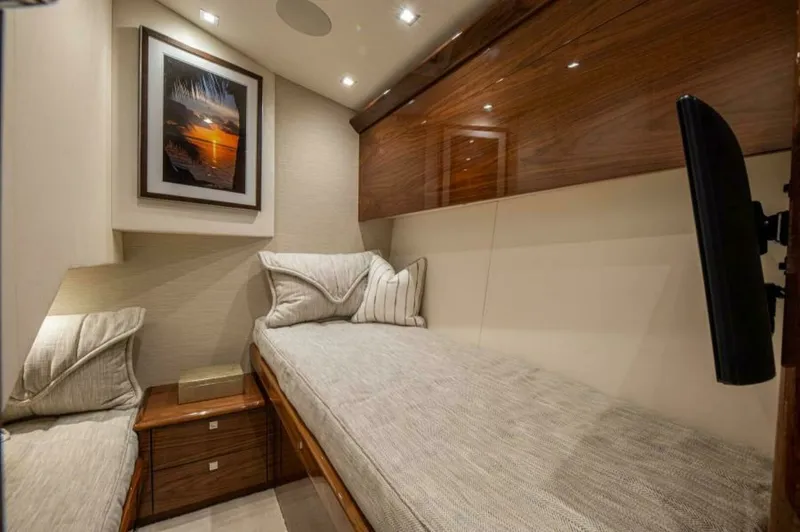 Slide: The Image of Cozy Twin Cabin with Wood Accents This inviting twin cabin on the 2023 Viking 64 Convertible 'Twin Reels' features elegant wood finishes and ambient recessed lighting. The comfortable twin beds are complemented by soft, neutral-toned linens and a sleek, mounted television for entertainmen - 7530848