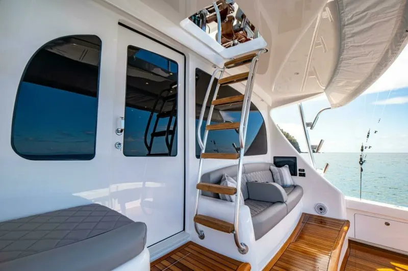 Slide: The Image of Flybridge Access and Aft Deck Seating This image showcases the elegant aft deck of the 2023 Viking 64 Convertible, featuring a comfortable seating area with plush cushions and a sleek, modern design. The high-quality teak decking complements the luxurious feel, while the sturdy ladder provide - 7530872