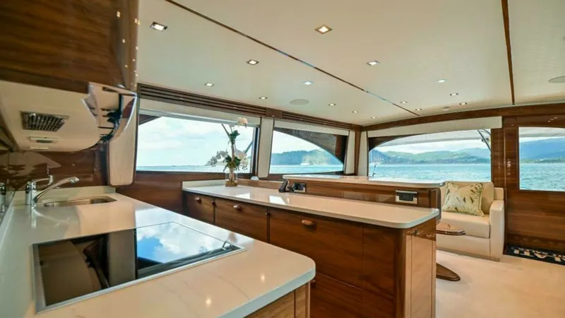 Slide: The Image of Spacious Salon with Galley View The salon of the 2023 Viking 64 Convertible is elegantly designed with panoramic windows offering breathtaking views. The galley features high-end appliances and sleek countertops, providing a perfect blend of functionality and style. Rich wood finishes a - 7600514