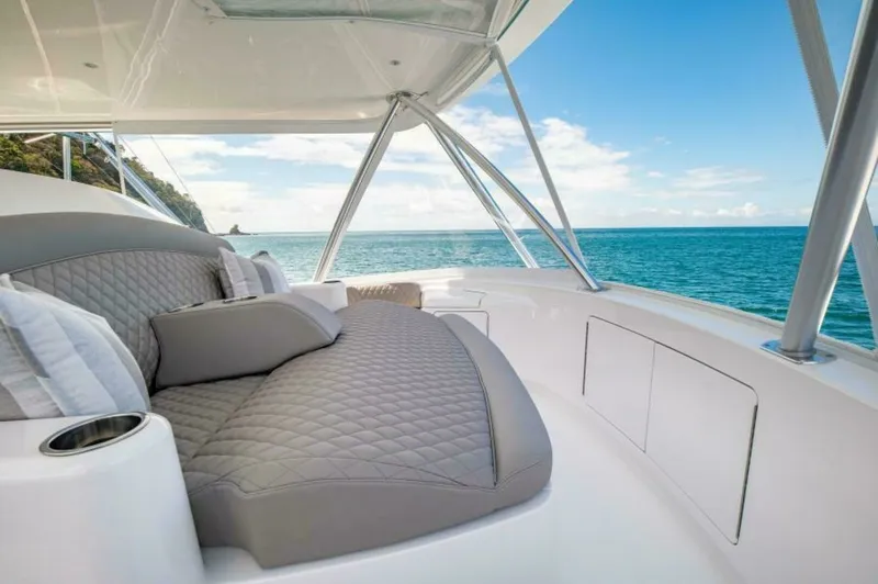 Slide: The Image of Flybridge Lounge with Ocean View This image showcases the luxurious flybridge lounge of the 2023 Viking 64 Convertible, featuring plush quilted seating with elegant grey upholstery. The area provides a perfect vantage point for enjoying panoramic ocean views, enhanced by the sleek design - 7530867