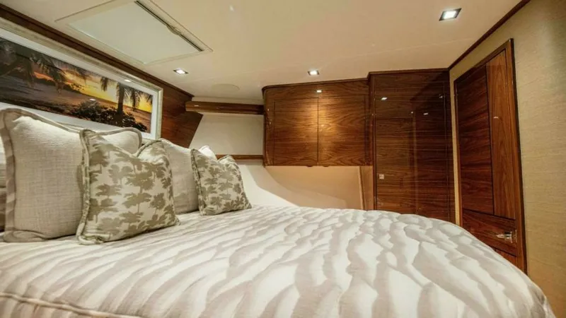 Slide: The Image of Master Stateroom with Luxurious Bedding The master stateroom of the 2023 Viking 64 Convertible features plush bedding complemented by elegant throw pillows, creating a serene and inviting atmosphere. Rich wooden cabinetry offers ample storage, while recessed lighting provides a warm and ambient - 7600539