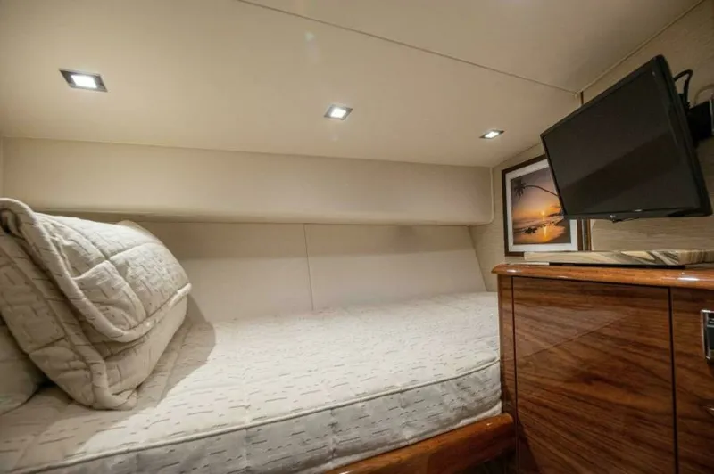 Slide: The Image of Guest Stateroom with Entertainment System This cozy guest stateroom on the 2023 Viking 64 Convertible offers a comfortable sleeping area with a plush mattress and elegant bedding. The room is equipped with an entertainment system, featuring a wall-mounted flat-screen TV for relaxation. Thoughtful - 7530852