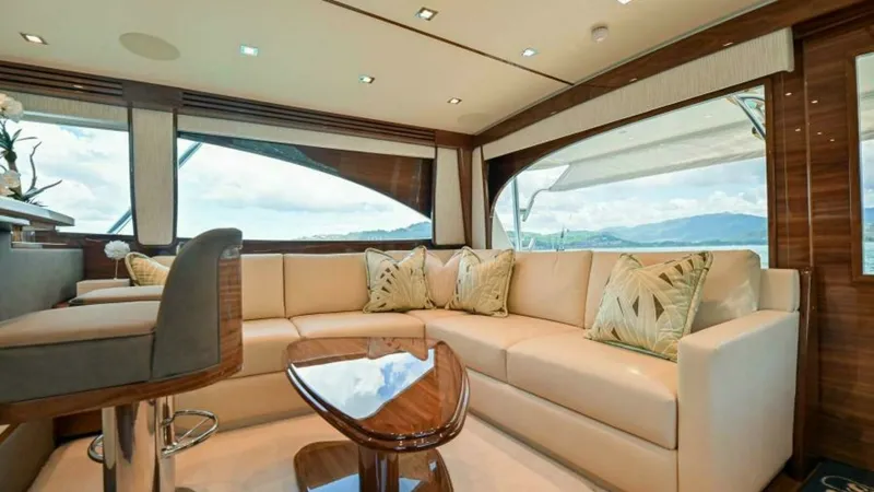 Slide: The Image of Luxurious Salon with Panoramic Views This elegant salon aboard the 2023 Viking 64 Convertible showcases a spacious seating area with plush, cream-colored upholstery. Large windows provide breathtaking panoramic views, creating a bright and inviting atmosphere. The polished wooden table and c - 7600511