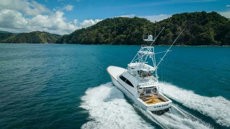 Slide: The Image of Aerial View of Aft Deck in Motion This dynamic aerial shot captures the Viking 64 Convertible, 'Twin Reels,' cruising through vibrant blue waters. The aft deck is visible, showcasing its spacious design ideal for fishing or leisure, complemented by the sleek lines and robust build typical - 7530886