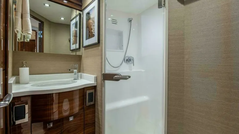 Slide: The Image of Luxurious Ensuite Bathroom This elegant ensuite bathroom features high-gloss wood cabinetry and modern fixtures, providing a touch of luxury on the Viking 64 Convertible. The spacious shower enclosure is complemented by sleek, recessed lighting, creating a bright and inviting atmos - 7600535