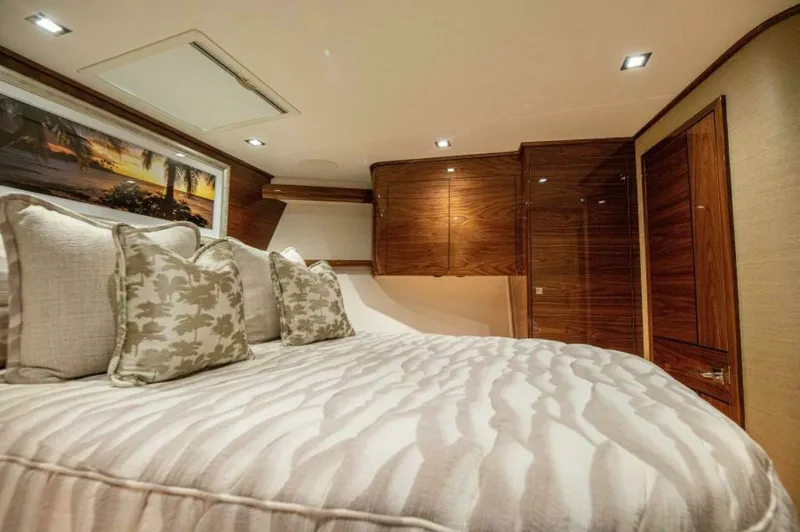 Slide: The Image of Master Stateroom with Luxurious Bedding The master stateroom of the 2023 Viking 64 Convertible features plush bedding complemented by elegant throw pillows, creating a serene and inviting atmosphere. Rich wooden cabinetry offers ample storage, while recessed lighting provides a warm and ambient - 7530857