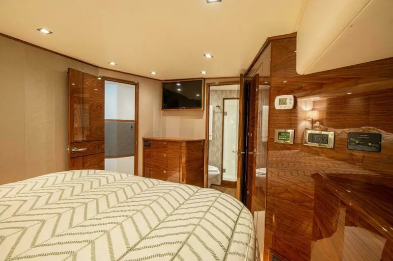 Slide: The Image of Luxurious Master Stateroom Interior The master stateroom of the 2023 Viking 64 Convertible offers an elegant retreat with high-gloss wood finishes and soft ambient lighting. The spacious layout features a plush, patterned bedspread, complemented by modern conveniences like a wall-mounted TV - 7530845