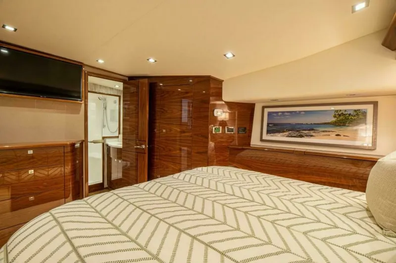 Slide: The Image of Luxurious Master Stateroom The master stateroom of the 2023 Viking 64 Convertible exudes opulence with its rich wood finishes and contemporary lighting. The room features a comfortable, stylish bedding arrangement complemented by a large flat-screen TV for entertainment. Elegant ca - 7530844