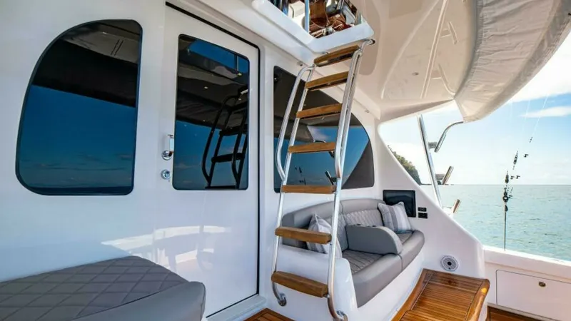 Slide: The Image of Flybridge Access and Aft Deck Seating This image showcases the elegant aft deck of the 2023 Viking 64 Convertible, featuring a comfortable seating area with plush cushions and a sleek, modern design. The high-quality teak decking complements the luxurious feel, while the sturdy ladder provide - 7600554