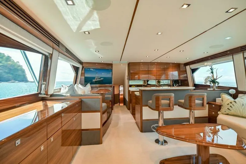 Slide: The Image of Spacious Salon with Panoramic Views The salon of the 2023 Viking 64 Convertible offers a luxurious and spacious environment, characterized by elegant wood finishes and expansive windows that provide panoramic ocean views. Comfortable seating arrangements and a sleek, modern bar area create - 7530824