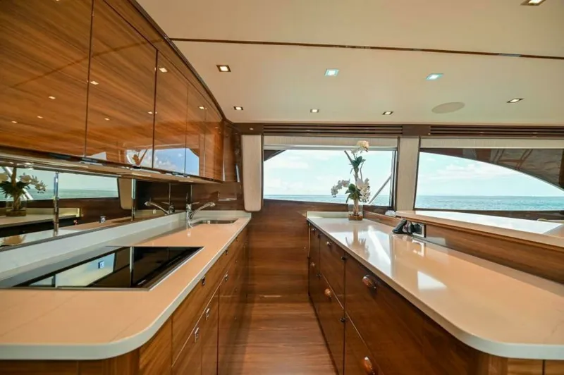 Slide: The Image of Galley with Elegant Wood Finish This stunning galley on the 2023 Viking 64 Convertible features a sleek and modern design with rich wood cabinetry and polished countertops. Large windows offer expansive ocean views, enhancing the sense of space and light. The area is equipped with top-o - 7530833