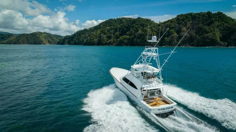 Slide: The Image of Aerial View of Aft Deck in Motion This dynamic aerial shot captures the Viking 64 Convertible, 'Twin Reels,' cruising through vibrant blue waters. The aft deck is visible, showcasing its spacious design ideal for fishing or leisure, complemented by the sleek lines and robust build typical - 7600568