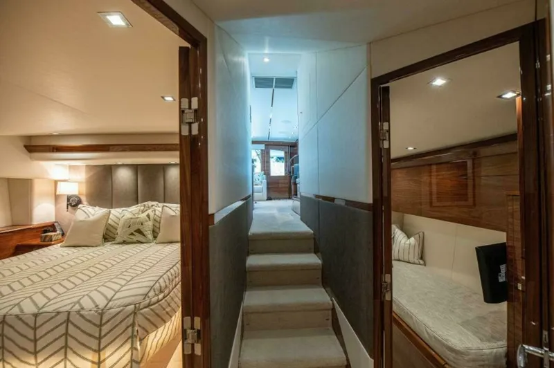 Slide: The Image of Lower Deck Corridor and Staterooms This image showcases the lower deck corridor of the 2023 Viking 64 Convertible, with access to luxurious staterooms. The master suite to the left features a spacious layout with a plush bed and elegant lighting. On the right, a cozy guest cabin provides a - 7530842