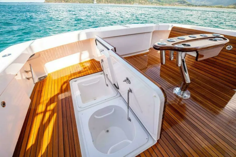 Slide: The Image of Teak Cockpit with Fishing Amenities This spacious cockpit on the 2023 Viking 64 Convertible features a beautifully finished teak deck, ideal for both relaxation and fishing activities. Equipped with a sturdy fishing station complete with rod holders and a built-in livewell, it offers conven - 7530875