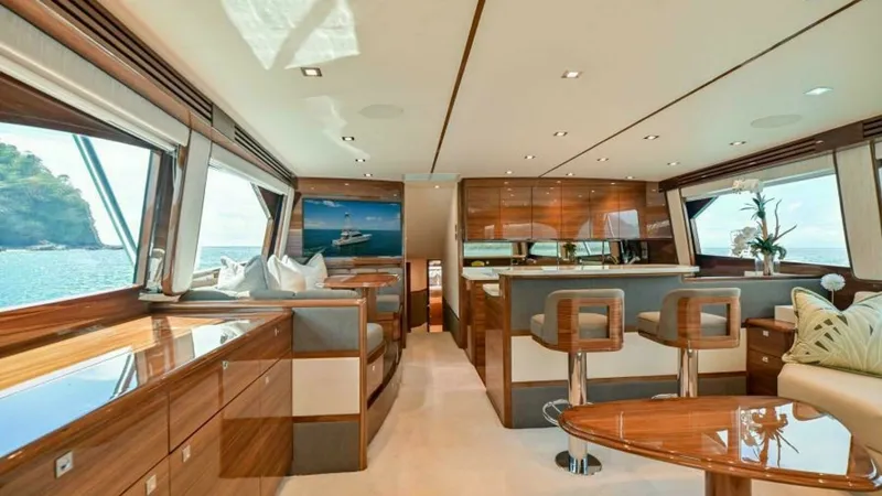 Slide: The Image of Spacious Salon with Panoramic Views The salon of the 2023 Viking 64 Convertible offers a luxurious and spacious environment, characterized by elegant wood finishes and expansive windows that provide panoramic ocean views. Comfortable seating arrangements and a sleek, modern bar area create - 7600506