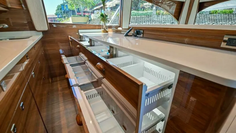 Slide: The Image of Galley with Ample Storage Drawers The galley of the 2023 Viking 64 Convertible features sleek, high-gloss wood cabinetry with multiple pull-out storage drawers, offering ample space for organizing culinary essentials. The expansive countertop provides a functional workspace, complemented - 7600518