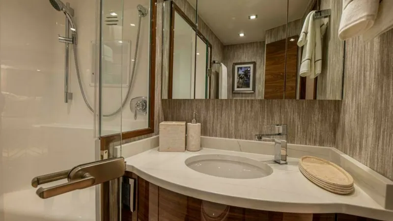 Slide: The Image of Elegant En-Suite Bathroom This luxurious en-suite bathroom on the Viking 64 Convertible features a modern glass-enclosed shower and sleek, polished fixtures. The elegant vanity is complemented by a rich wood finish and a pristine countertop, offering both style and functionality. - 7600528