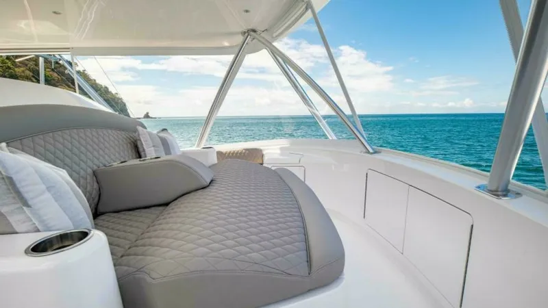 Slide: The Image of Flybridge Lounge with Ocean View This image showcases the luxurious flybridge lounge of the 2023 Viking 64 Convertible, featuring plush quilted seating with elegant grey upholstery. The area provides a perfect vantage point for enjoying panoramic ocean views, enhanced by the sleek design - 7600549