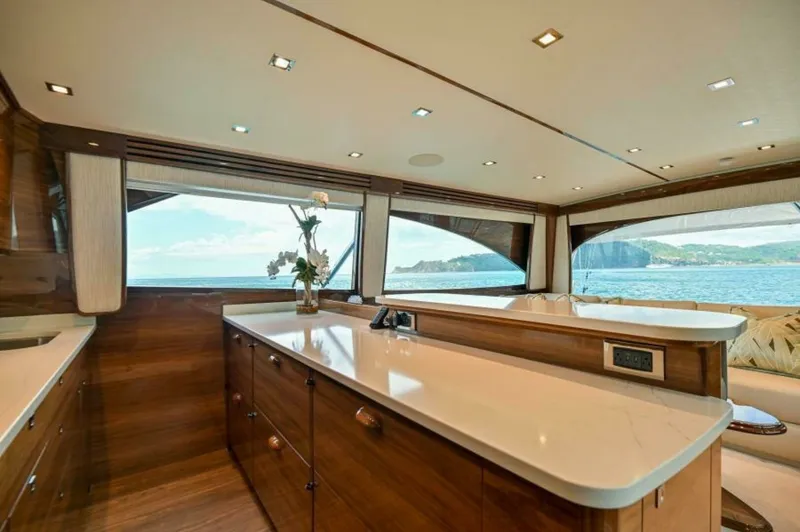 Slide: The Image of Galley and Salon with Ocean Views This elegant galley in the 2023 Viking 64 Convertible features sleek, polished wood cabinetry and expansive countertops, offering ample space for culinary preparation. Large windows flood the area with natural light and provide stunning panoramic views of - 7530835