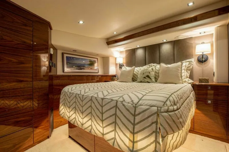 Slide: The Image of Luxurious Master Stateroom This elegant master stateroom aboard the 2023 Viking 64 Convertible features rich wood finishes and ambient lighting. The plush bedding and padded headboard create a cozy yet upscale atmosphere, while built-in storage ensures a clutter-free environment. M - 7530843