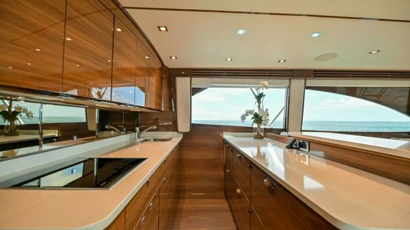 Slide: The Image of Galley with Elegant Wood Finish This stunning galley on the 2023 Viking 64 Convertible features a sleek and modern design with rich wood cabinetry and polished countertops. Large windows offer expansive ocean views, enhancing the sense of space and light. The area is equipped with top-o - 7600515