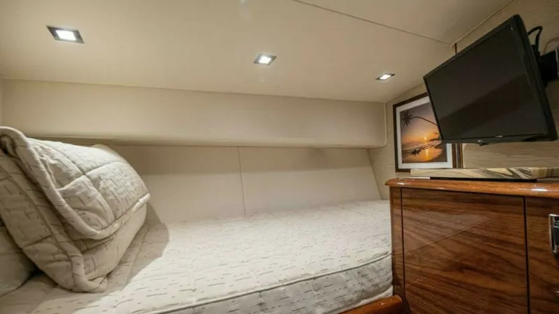 Slide: The Image of Guest Stateroom with Entertainment System This cozy guest stateroom on the 2023 Viking 64 Convertible offers a comfortable sleeping area with a plush mattress and elegant bedding. The room is equipped with an entertainment system, featuring a wall-mounted flat-screen TV for relaxation. Thoughtful - 7600534